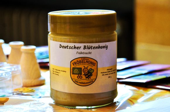 Honig Gläserner Behälter mit deutscher Blütenpollen, etikettiert und auf einem Tisch.