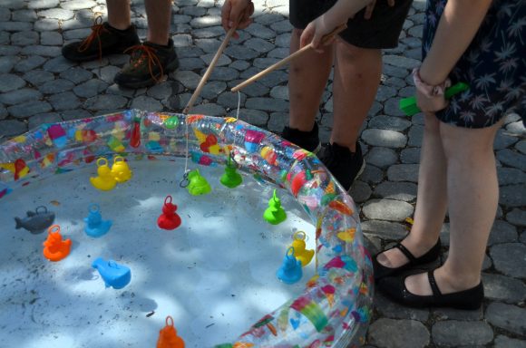 Entenangeln Kinder fischen mit Stöcken farbige Gummienten aus einem Wasserbecken.