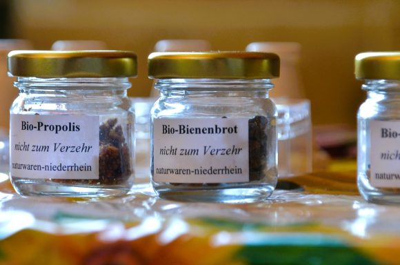 Propolis Glasbehälter mit Etiketten für Propolis und Bienenhonig, auf einer bunten Unterlage.